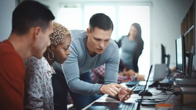 3 Key components to getting the digital workplace right blog main image a group of people looking at a computer screen together.