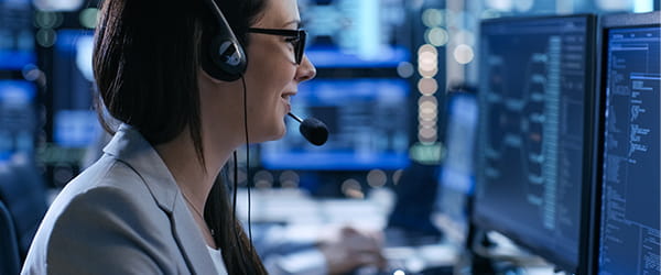 a women wearing glasses and headphone in front of a screen