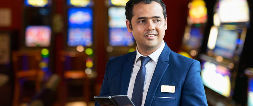Casino staff member in a suit holding a tablet