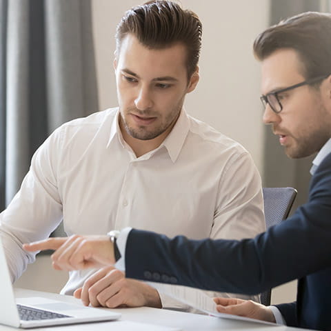 a man and a woman sitting at a table looking at a laptop a man and a woman sitting at a table looking at a laptop