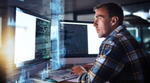 A man looking at code on a computer screen