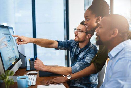 IT workers pointing at monitor for blog post