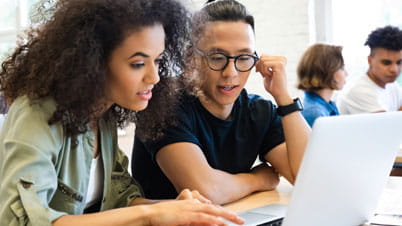 two persons in front of a laptop