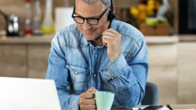 A man wearing headphones and holding a cup of coffee A man wearing headphones and holding a cup of coffee