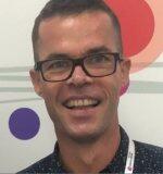 a man wearing glasses and smiling at the camera