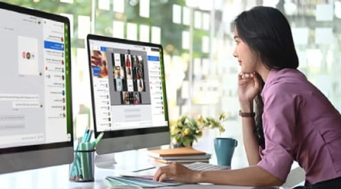Woman working at a desk using two monitors