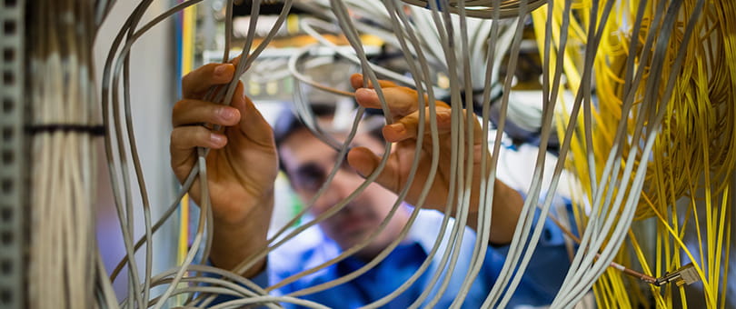 An individual handling multiple network cables inside a server or telecommunications rack