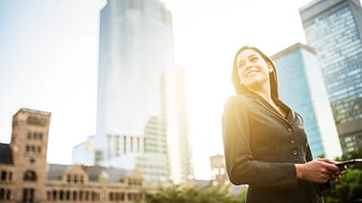 woman using mobile phone with tall buildings in the background