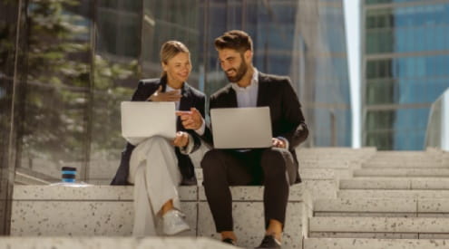 a man and woman looking at laptops