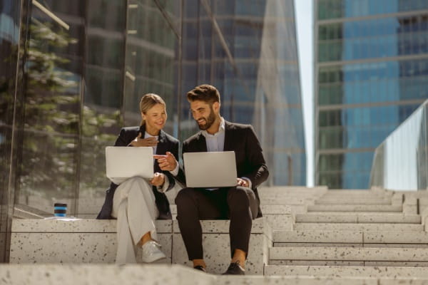 A woman and man looking at laptops A woman and man looking at laptops
