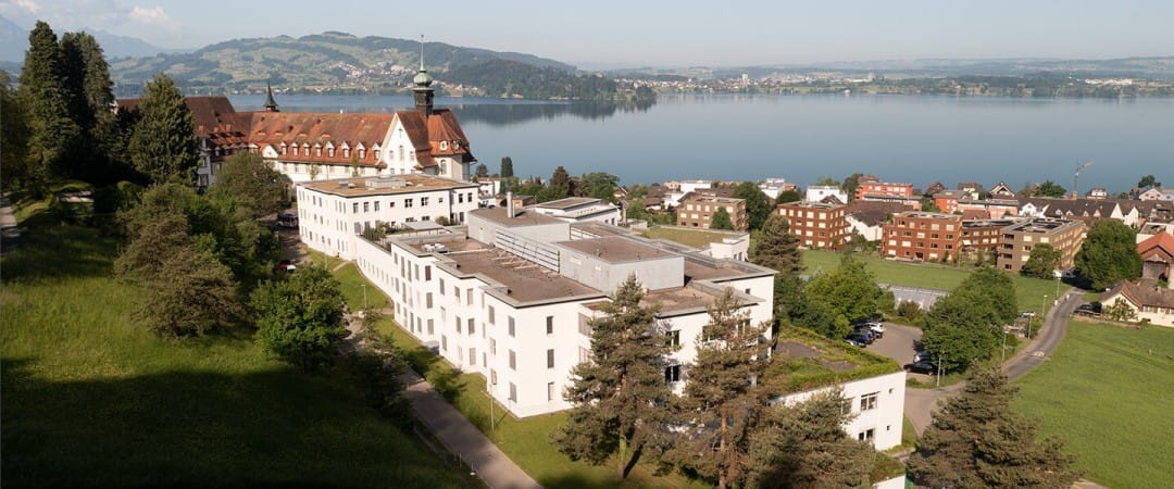 Triaplus AG a large building by a body of water